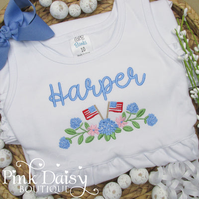 White toddler dress with personalized embroidery of name Harper in soft blue, pastel floral hydrangeas, and two small American flags. Features a sleeveless design and ruffled hem, perfect for patriotic celebrations, summer photos, and handmade holiday outfits.