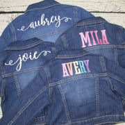 Kids denim jackets embroidered with names.  Aubrey and Joie is in cursive letters with white thread.  Mila is in block letters in pink thread.  Avery is in block letters in rainbow thread.